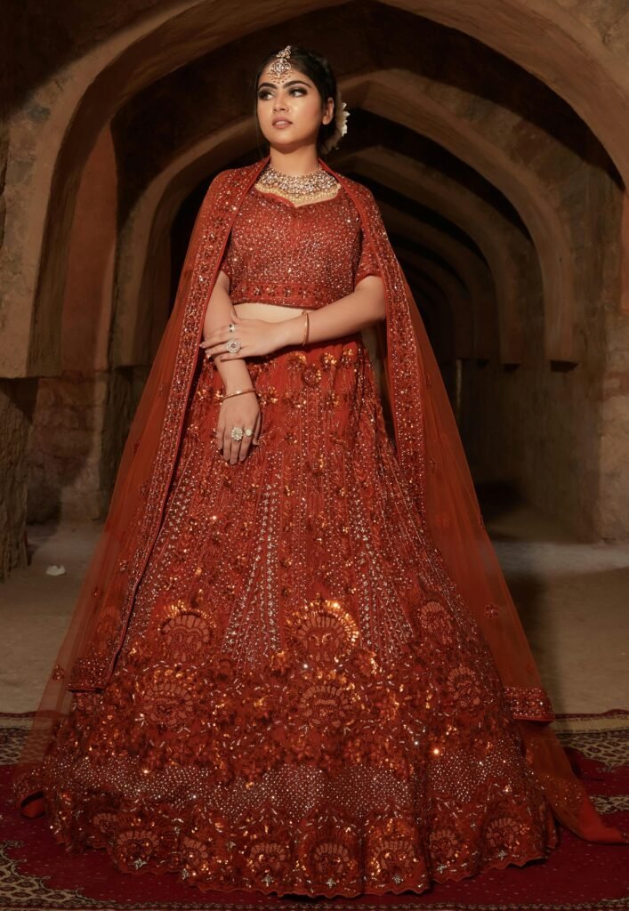 Graceful Indian woman in red bridal attire with intricate embroidery, showcasing cultural fashion.
