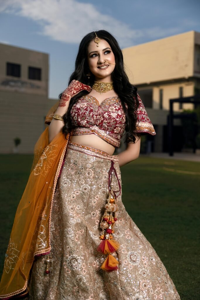 Beautiful Indian bride wearing traditional attire with intricate jewelry, posing outdoors in a festive setting.