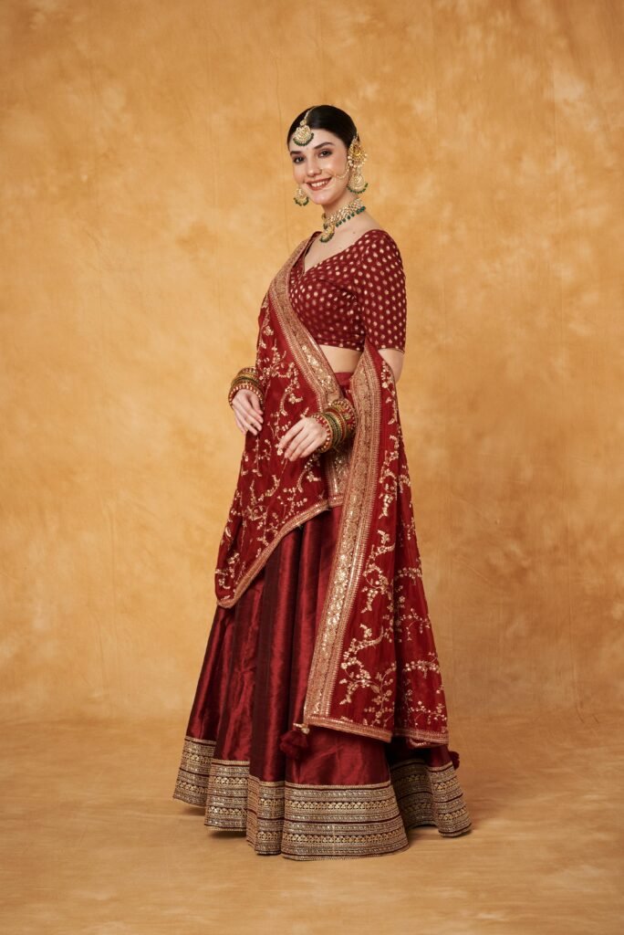 Elegant Indian woman in a red lehenga with intricate embroidery, posing with grace.